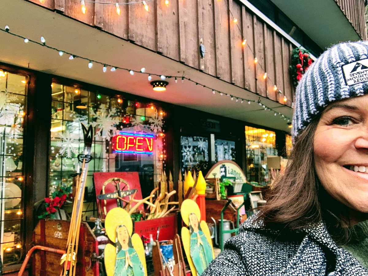 Kit smiling in front of a kitschy antique store stuffed with Christmasy decor in Fort Langley, BC